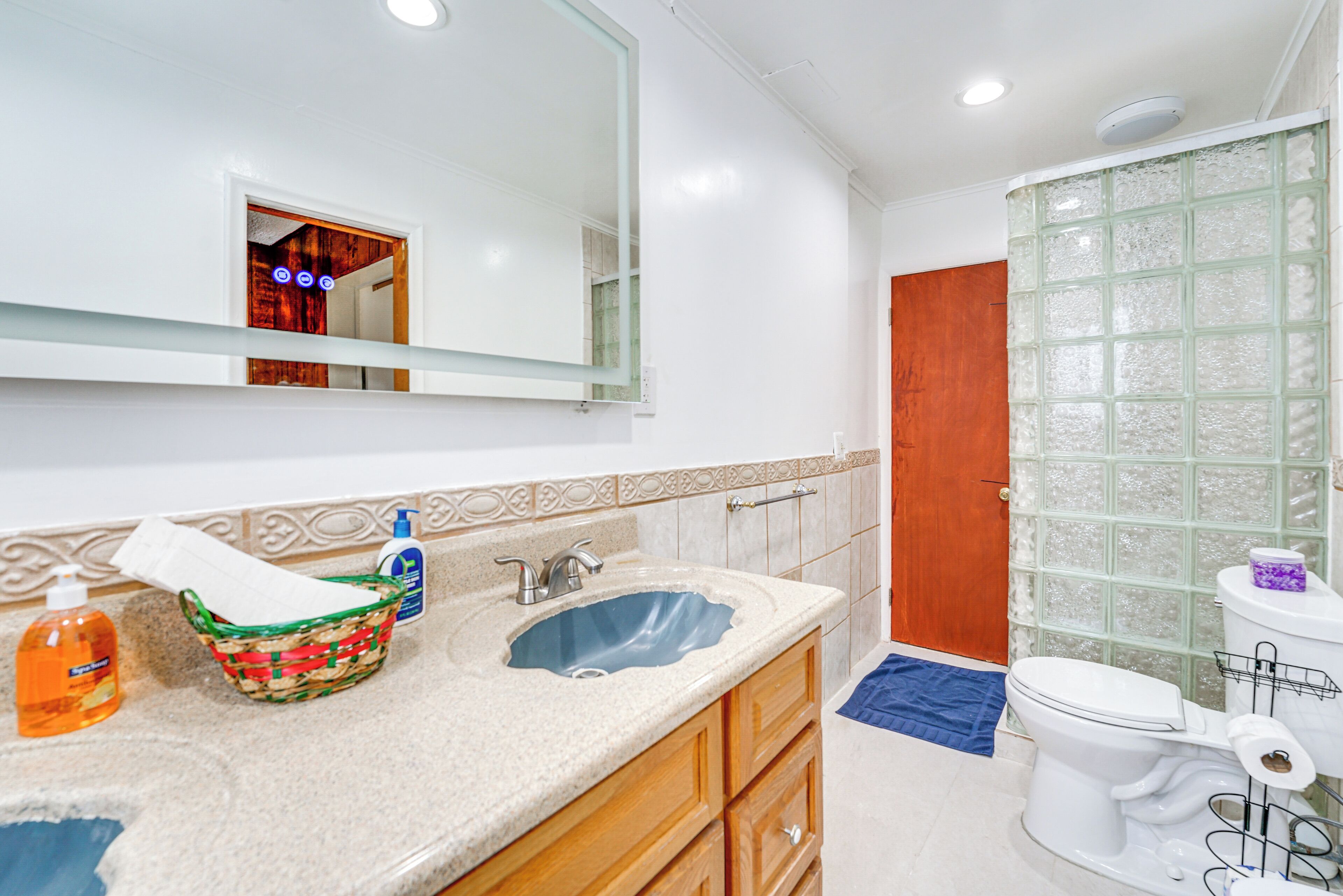 Un baño con lavamanos, espejo e inodoro.