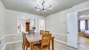 Un comedor con una mesa y sillas de madera, un candelabro y vista a la cocina.