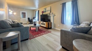 Una sala de estar con dos sofás, una mesa de centro, un televisor, una chimenea y una puerta.