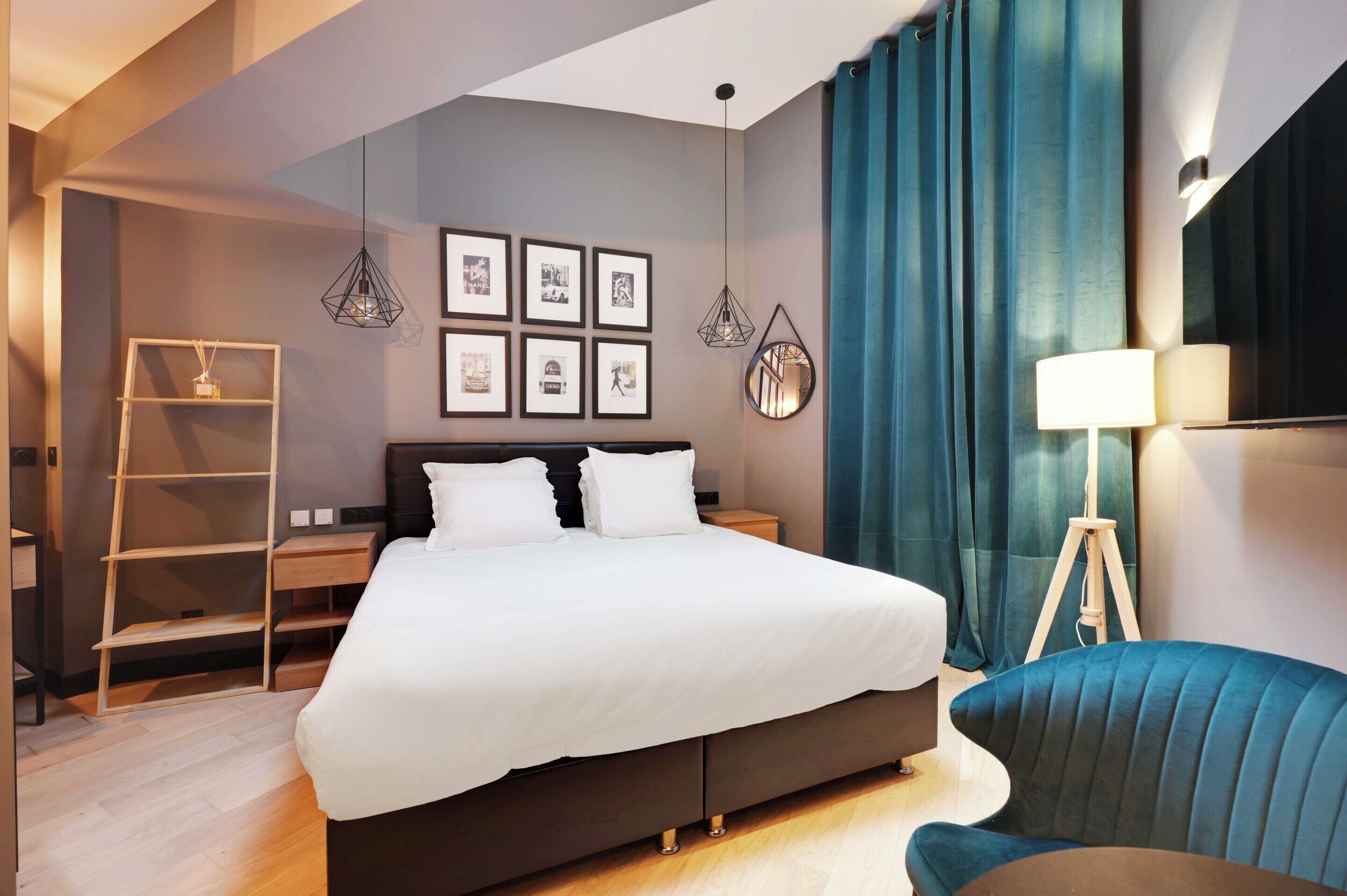 Et moderne hotelværelse med en stor seng, et skrivebord, en stol og en skrivebordslampe.