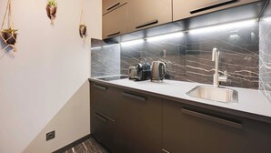 Cozinha moderna com painel de fundo de mármore, eletrodomésticos de aço inoxidável e três vasos suspensos.