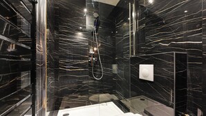 Um banheiro moderno com chuveiro em cabine de vidro, vaso sanitário separado e banheira.