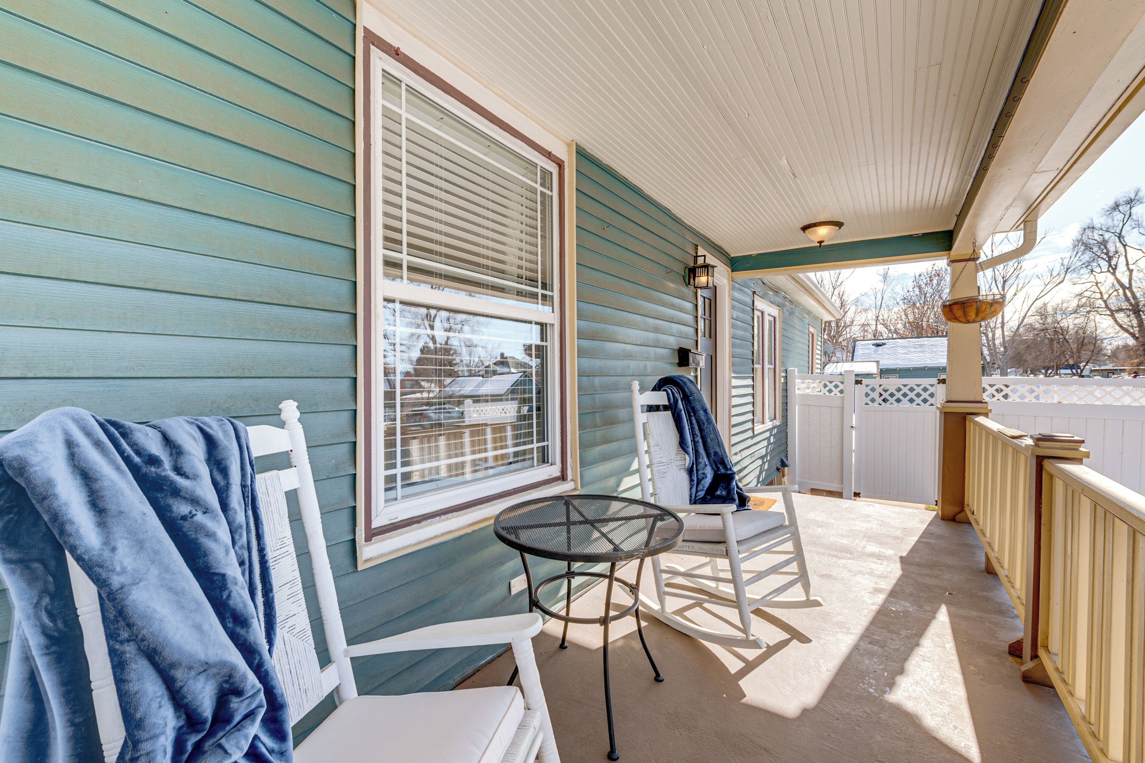 A porch with a table and chairs, a covered area, and a view of the neighborhood.