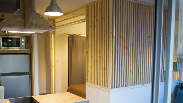 A compact kitchen with a wooden countertop, a built-in microwave, and a hanging light fixture.