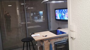 A modern kitchen with a wooden island, a built-in oven, a large window with blinds, and a ceiling-mounted light fixture.