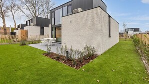 A modern house with a flat roof, large windows, and a well-maintained lawn.