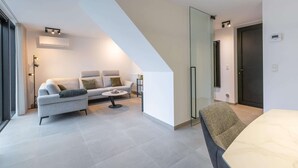 A modern living room with a sofa, coffee table, and a dining area with a table and chair.