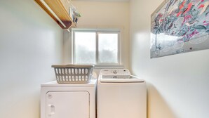 Un espace buanderie comprenant un lave-linge, un sèche-linge, une fenêtre et une affiche accrochée au mur.