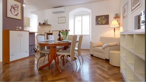 Ein modernes Wohnzimmer mit Esstisch, Stühlen, einer Couch und einer Lampe.