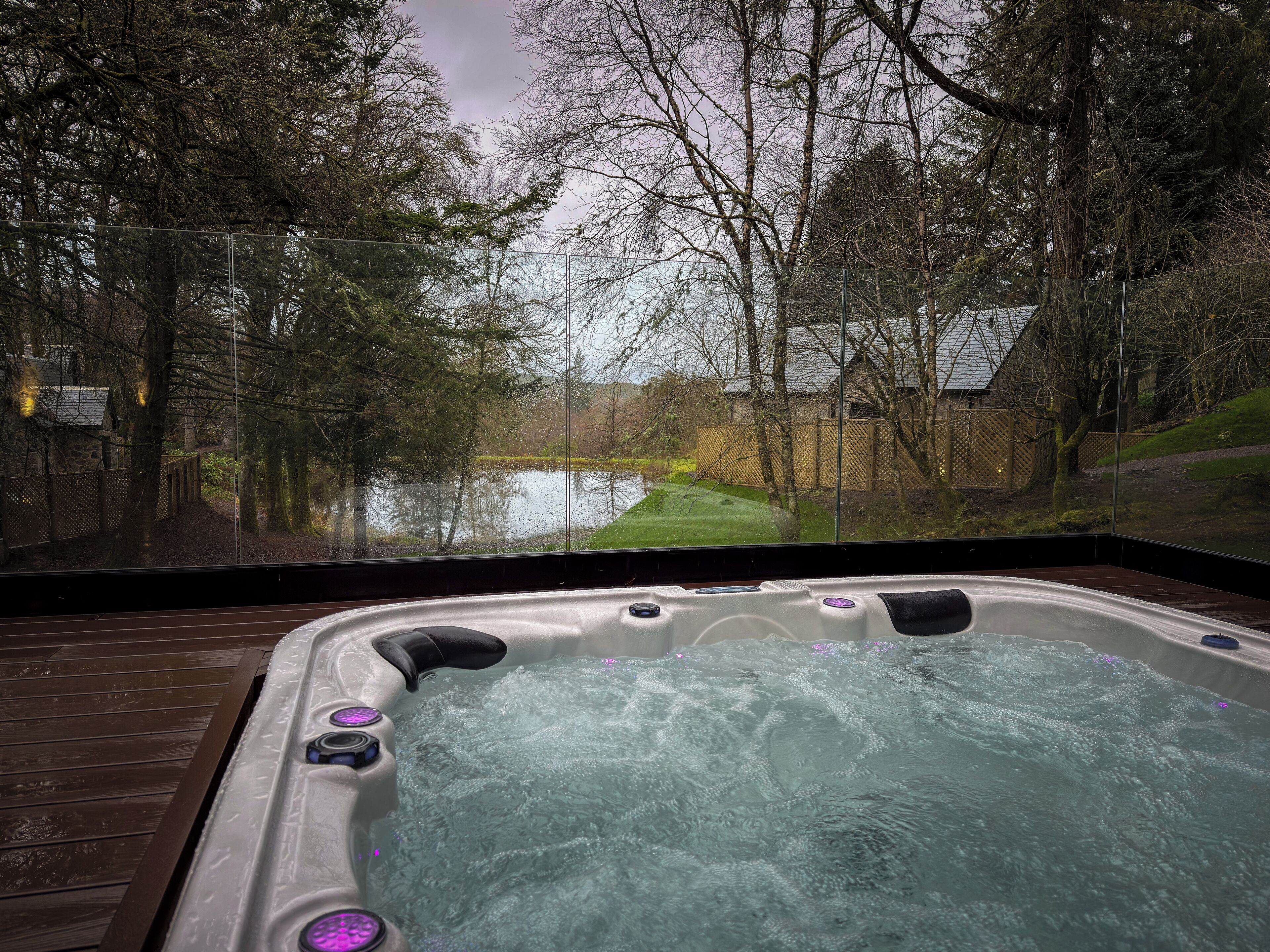 Un jacuzzi con vista a un estanque y árboles.