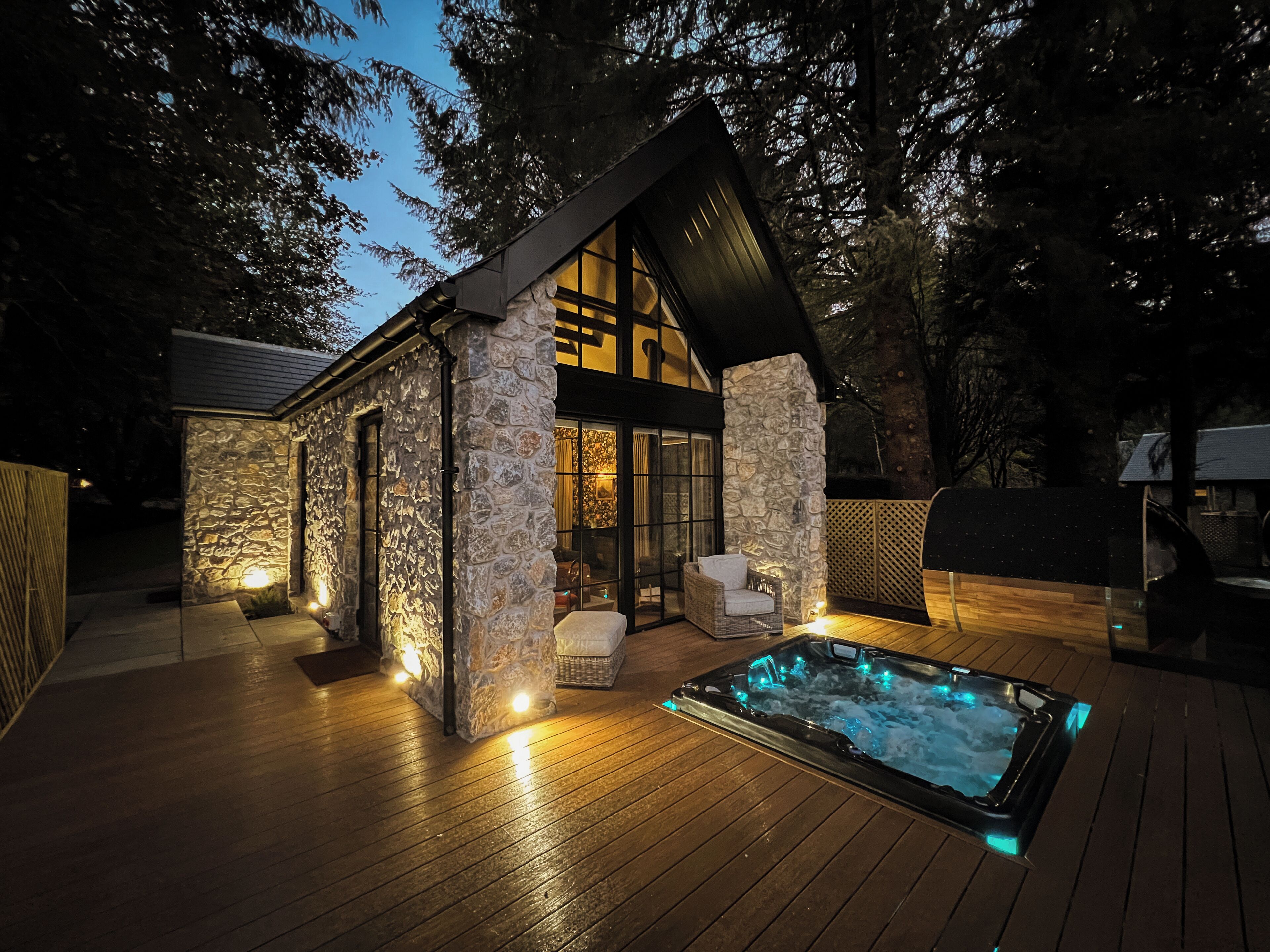 A stone cabin with a hot tub and outdoor seating.