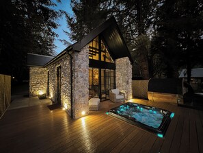 A stone cabin with a hot tub and outdoor seating. - Glencruitten House (Oban)