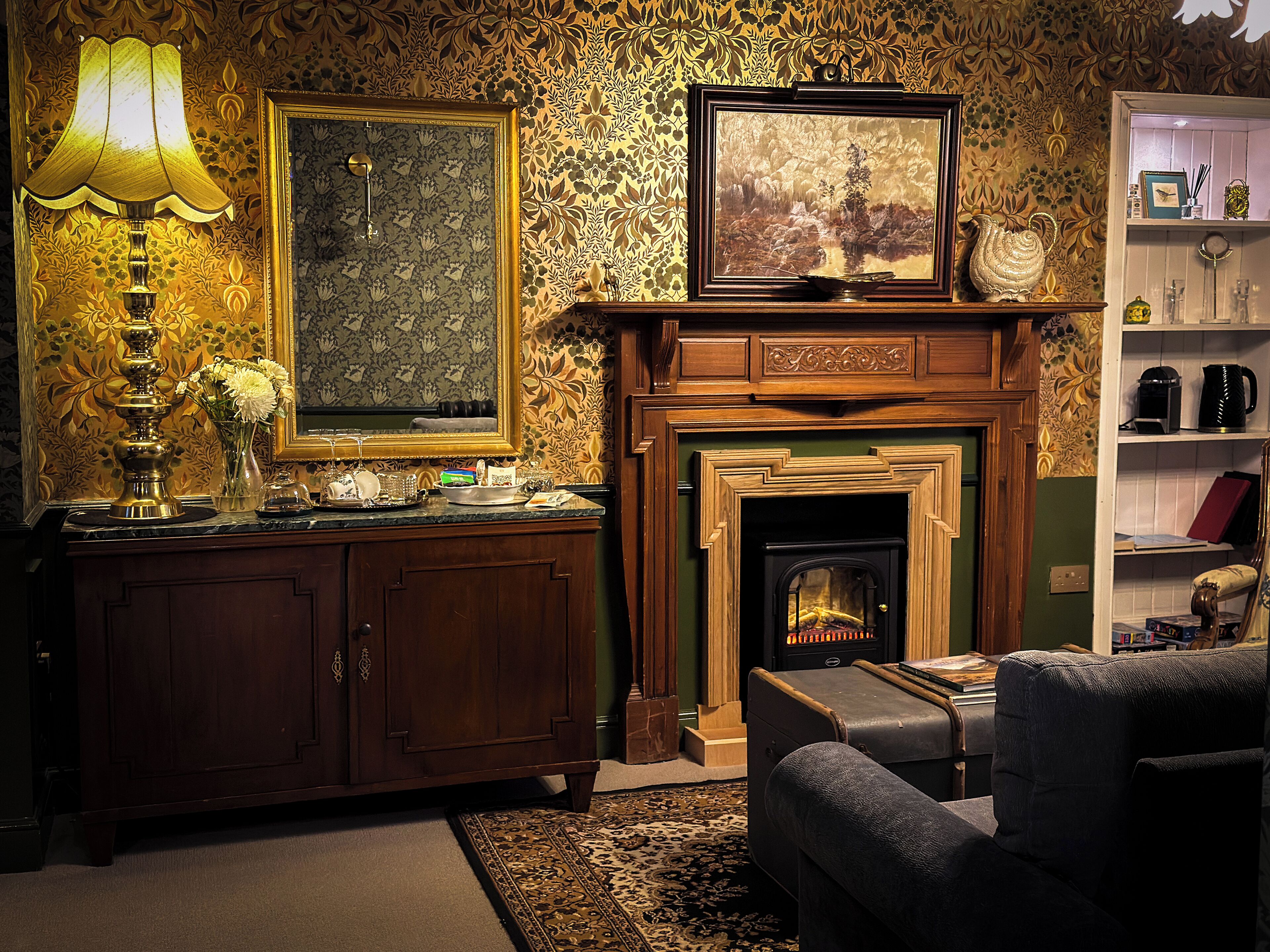 A cozy living room with a fireplace, a wooden cabinet, and a lamp.