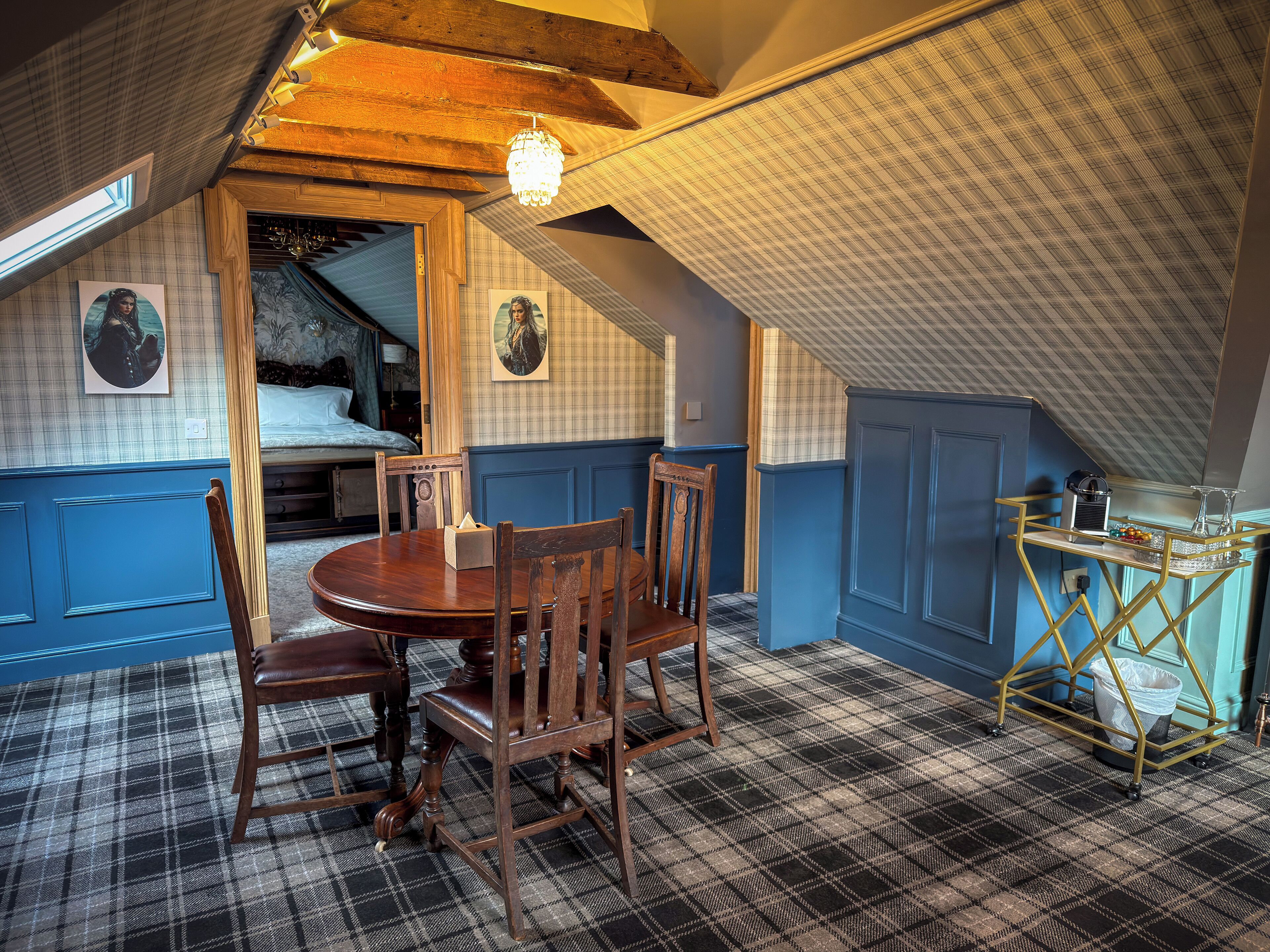 A dining area with a wooden table and chairs, a chandelier, and a checkered floor.