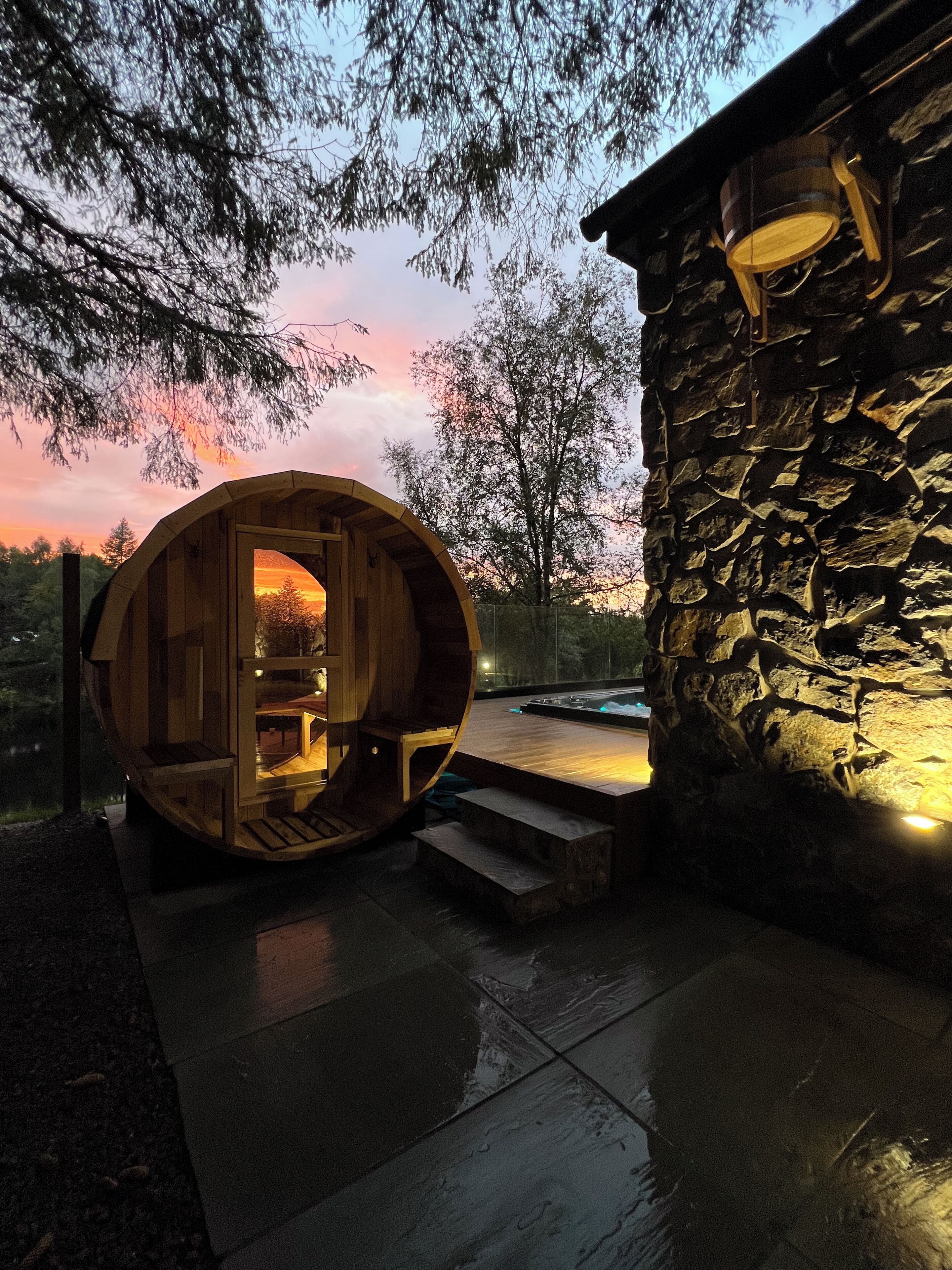 A wooden cabin with a circular entrance, a stone building, and a pool area.