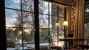 Una habitación acogedora con chimenea, un amplio ventanal con vistas a árboles y una zona de estar confortable.