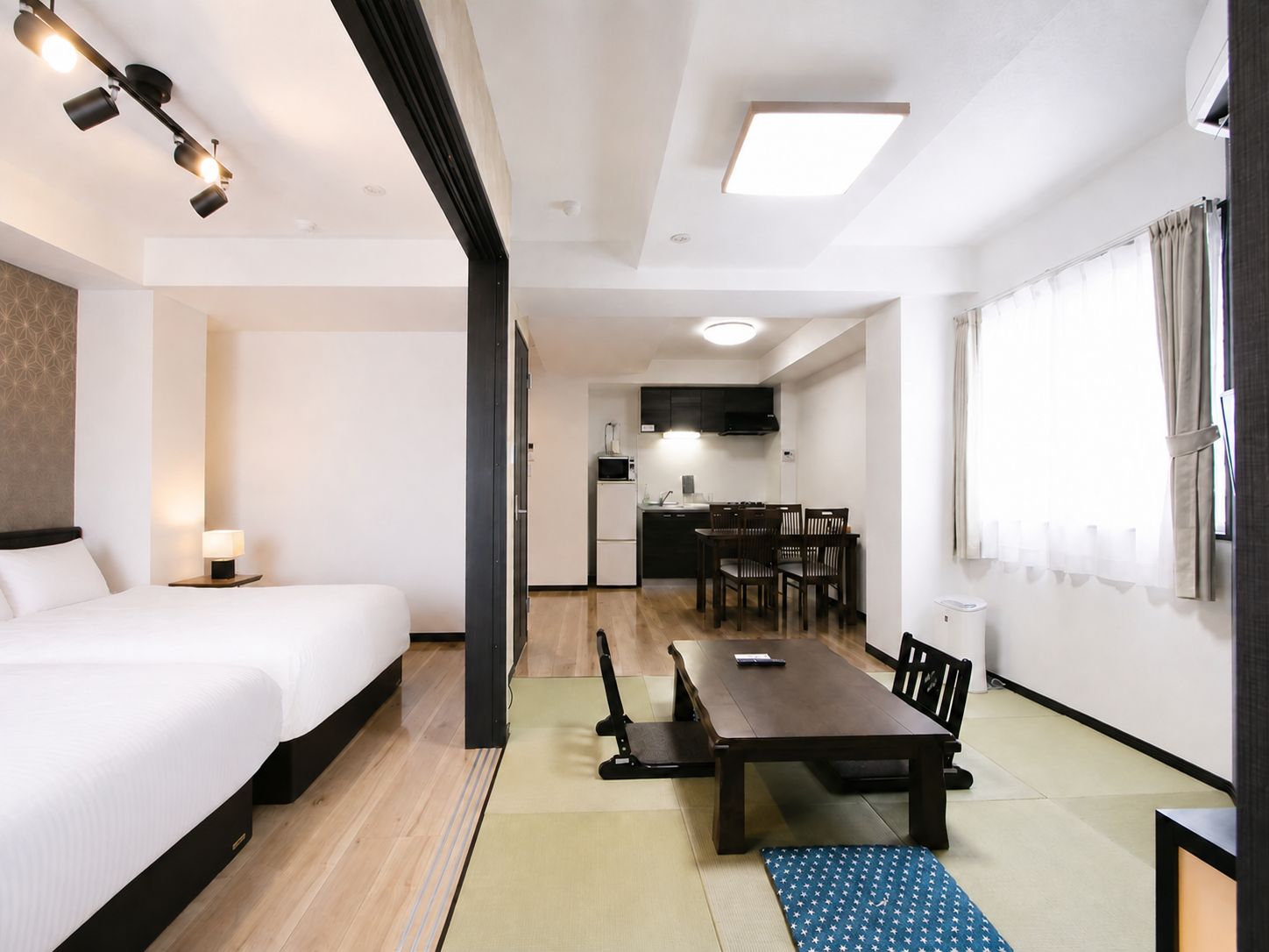Habitación de hotel con cama, escritorio, mesa de comedor y kitchenette.