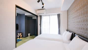 A hotel room with two beds, a large mirror, an air conditioning unit, and a window with curtains.