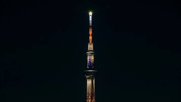 A tall, illuminated tower with a spire at the top, set against a dark night sky.
