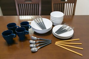 A dining table with blue mugs, stacked white plates, silverware, and chopsticks. - Randor Residence Tokyo Annex (Tokyo)