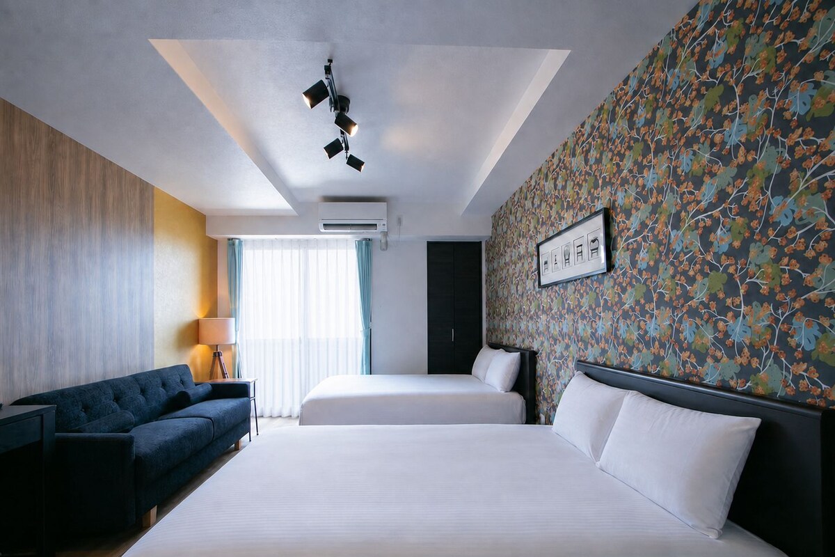 Une chambre d’hôtel avec un grand lit, un canapé, un bureau et un mur décoré de motifs.