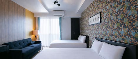 A hotel room with a large bed, a sofa, a desk, and a patterned wall.