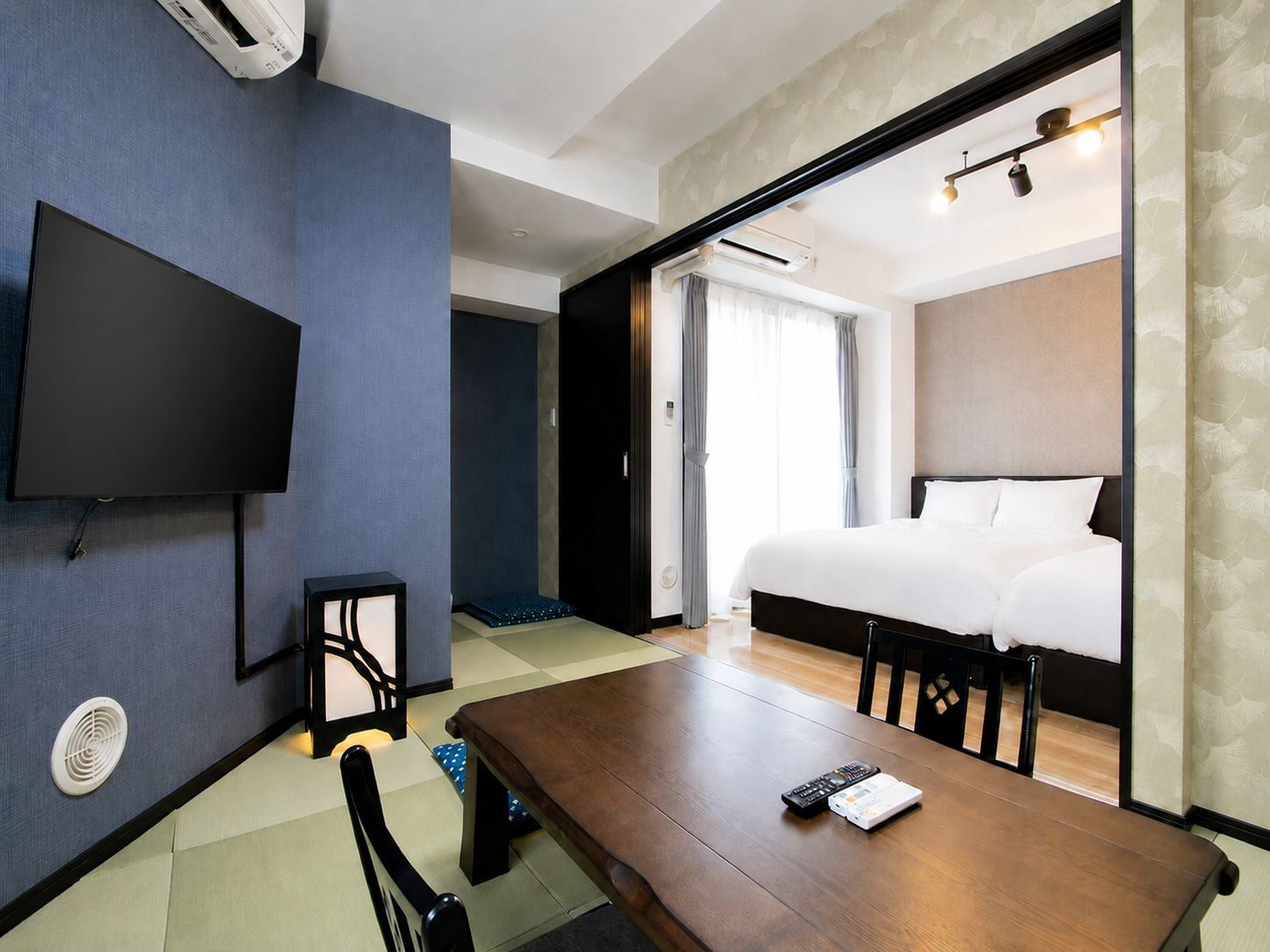 Ein Hotelzimmer mit Bett, Flachbildfernseher an der Wand, Holztisch und Stuhl.