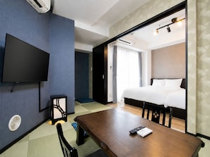 A hotel room with a bed, a flat-screen TV mounted on the wall, a wooden table, and a chair. - Randor Residence Tokyo Annex (Arakawa-ku)