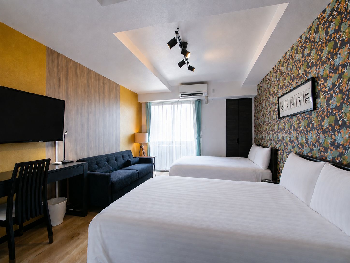 A hotel room with a bed, a desk, a chair, a television, and a wardrobe.
