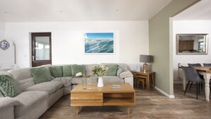A modern living room with a sectional sofa, a wooden coffee table, and a painting on the wall. - Wheal Frances -Hot Tub - Free Parking - Free Wi-Fi - Accessible (Helston)