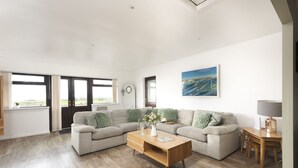A spacious living room with a large sofa set, a wooden coffee table, and a painting on the wall. - Wheal Frances -Hot Tub - Free Parking - Free Wi-Fi - Accessible (Helston)