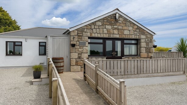 A stone building with a wooden deck and a gravel pathway leading to a gated entrance. - Wheal Frances -Hot Tub - Free Parking - Free Wi-Fi - Accessible (Helston)