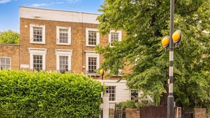 A building with multiple windows and a hedge in front. - House in Central London - Sleeps up to 16 (London)