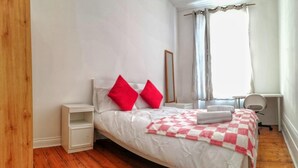 A bedroom with a bed, two nightstands, a chair, a desk, and a window with curtains. - House in Central London - Sleeps up to 16 (London)