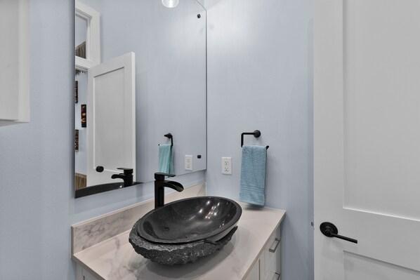 A bathroom with a white sink, black faucet, and a large mirror.