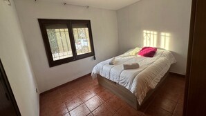 A bedroom with a bed, a ceiling fan, a window with bars, and a tiled floor. - Ideal Holiday Rental House for Families Near the Beach (Calonge)