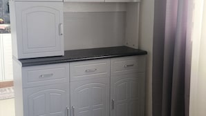 Una cocina con gabinetes grises, encimera negra y una ventana con cortinas grises.
