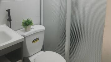 Baño con inodoro, lavabo y una pequeña planta en maceta.