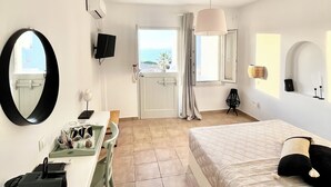 Une chambre d’hôtel avec un lit, un bureau et une vue sur la mer.