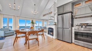 A modern kitchen with a built-in oven, a stainless steel refrigerator, and a dining area with a round table and chairs.