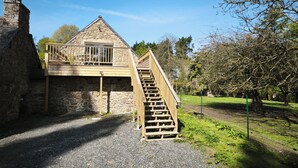 A stone building with a wooden staircase leading to a balcony. - Guergonet, Cosy 2-bedroom accomodation (Châtelaudren-Plouagat)