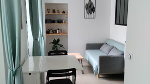 Ein gemütlicher Wohnbereich mit Esstisch, Sofa und einer Regalwand mit Dekoration.