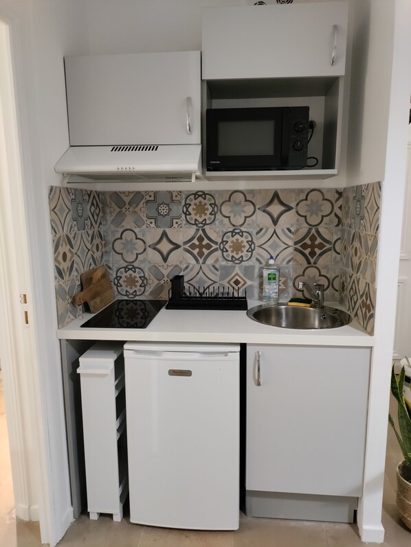 A compact kitchen with a microwave, stove, and sink.