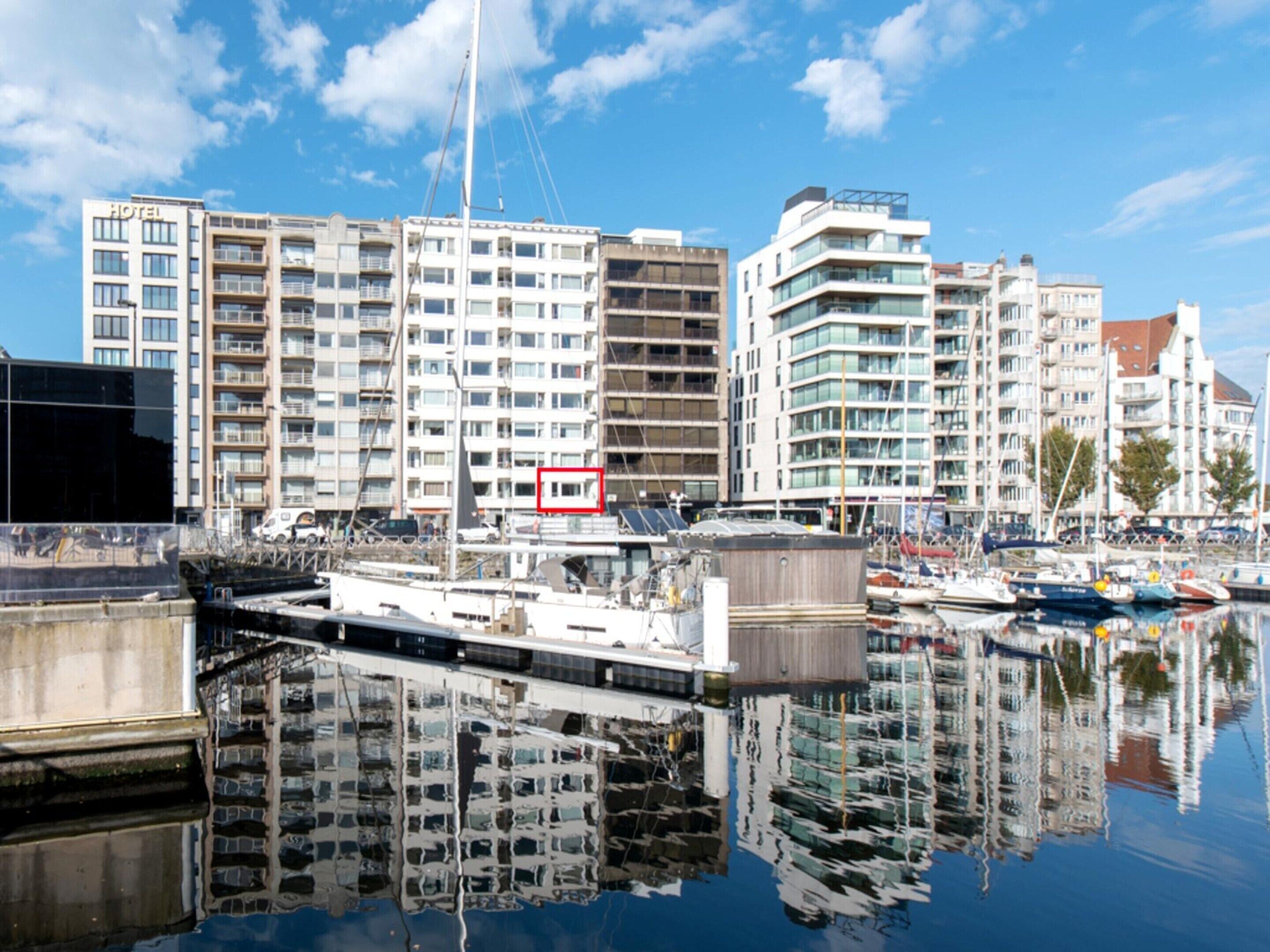 A marina with modern buildings, including a hotel with multiple floors and balconies.