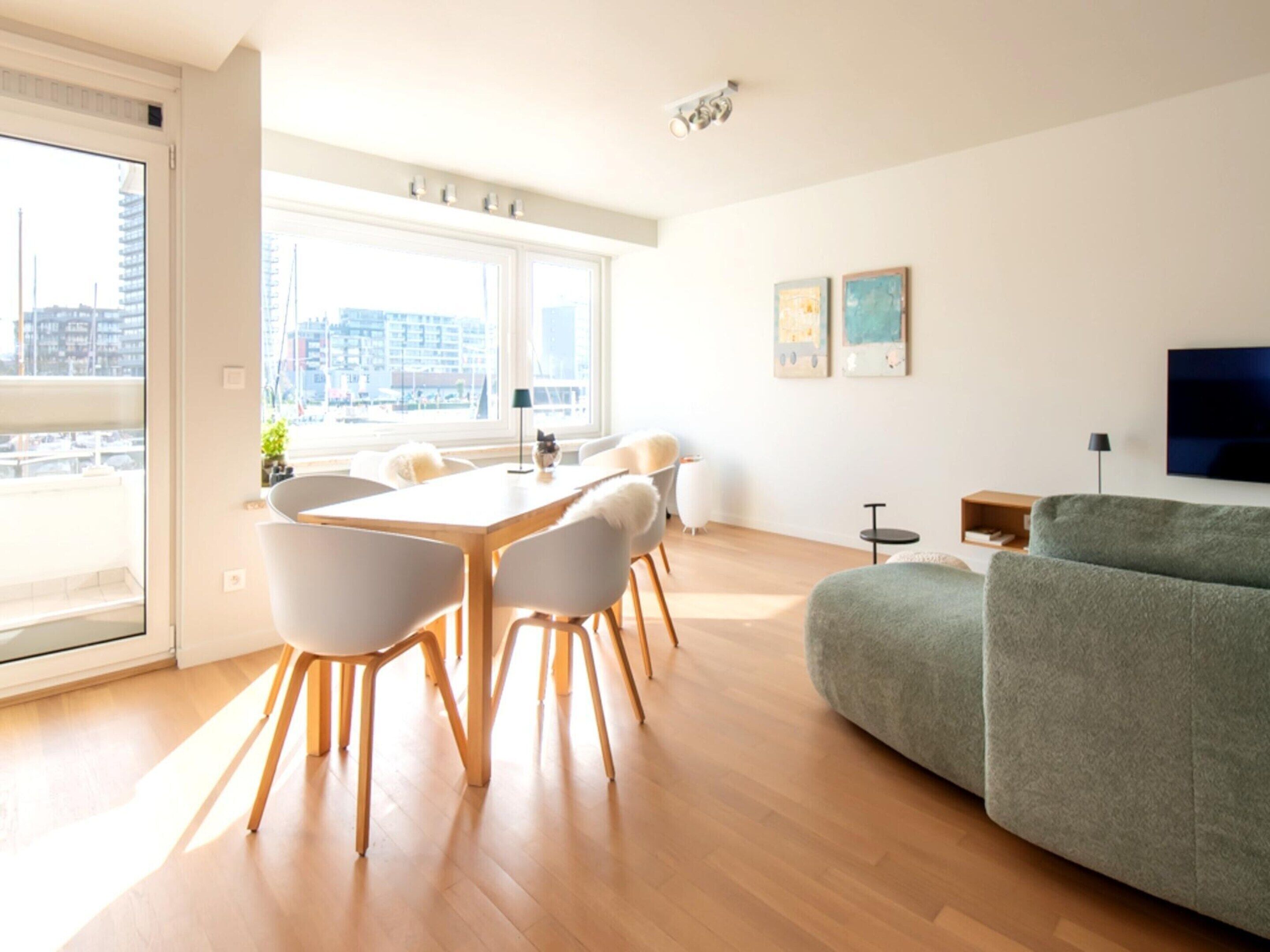 Un soggiorno moderno con zona pranzo, ampie finestre e vista sulla città.