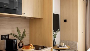Cocina compacta con un microondas Bosch, una cafetera y un florero con una planta.