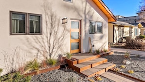A modern house with a beige exterior, a wooden front door, and a small porch with steps. - Hot Tub Hideout | Old Town’s Best Group Stay (Fort Collins)