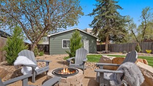 A backyard with a fire pit, two Adirondack chairs, and a small shed. - Hot Tub Hideout | Old Town’s Best Group Stay (Fort Collins)