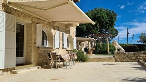 A stone building with a covered patio, outdoor seating, and a lion statue. - Gîte Lucas 4 pers. piscine et clim à Sommières - Calm, nature & traditions ! (Sommières)