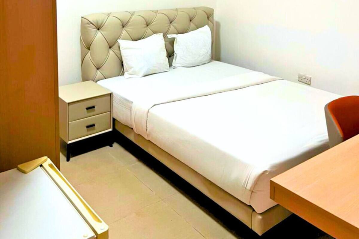 Un dormitorio ordenado con cama, mesita de noche y una silla.